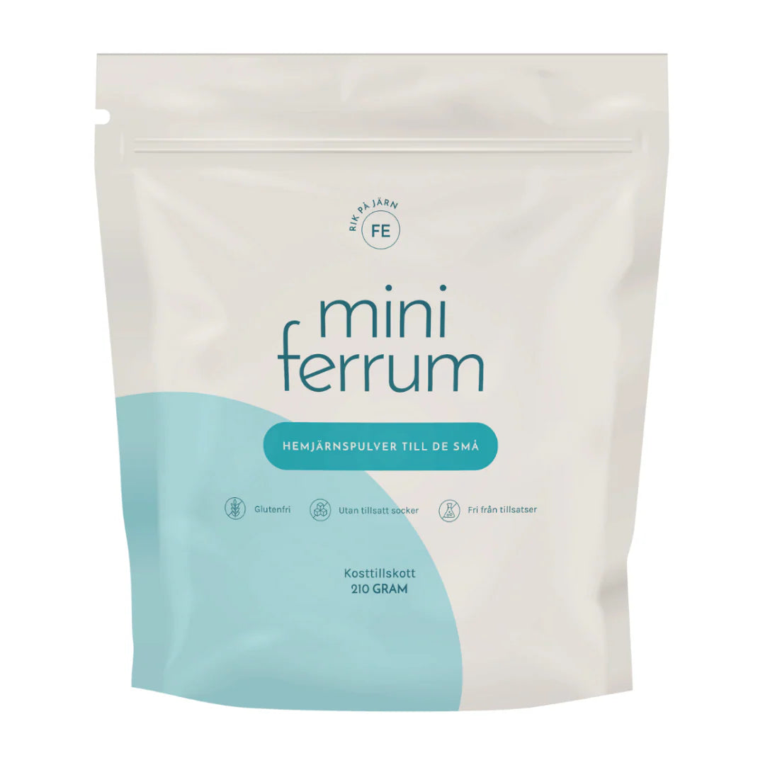 Mini Ferrum Lasten Hemirautajauhe; valkoinen ja vaaleansininen uudelleensuljettava mini ferrum -rautalisäjauhepussi lapsille; pussi mattapintainen pyöristetyin kulmin; pääteksti mustalla groteskikirjasimella, pienempi teksti mainitsee gluteenittomuuden, sokerittomuuden ja lisäaineettomuuden; nettopaino 210 grammaa merkitty pakkaukseen; tausta valkoinen, ei rekvisiittaa tai ihmisiä.