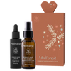 Moi Forest Forest Hydration Duo; kaksi MoiForest-ihonhoitotuotetta — Forest Glow Serum ja Forest Rain Face Mist — esillä mattapintaisen ruskean suorakaiteen muotoisen lahjarasian vieressä valkoisin lehti- ja tähtikuvioin; seerumi pienessä kirkkaassa lasipullossa tippakannella, sumute korkeammassa suihkepullossa; molemmissa minimalistiset etiketit groteskitekstillä; tausta neutraali; ei ihmisiä tai käsiä.