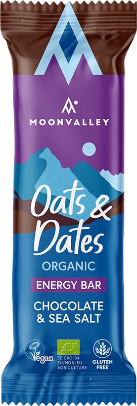 Moonvalley Luomu Energiapatukka Suklaa & Merisuola; Moonvalley-luomuenergiapatukka suklaa- ja merisuola-maussa, merkitty Oats & Dates; vegaaninen ja gluteeniton urheiluravintopatukka mattaa sinistä ja violettia muovikääreessä, tyylitelty vuorikuvitus ja useita sertifiointilogoja; tuotenimi lihavoidulla groteskilla; tausta tasainen, ei ihmisiä tai esineitä, lähikuva keskitettynä.