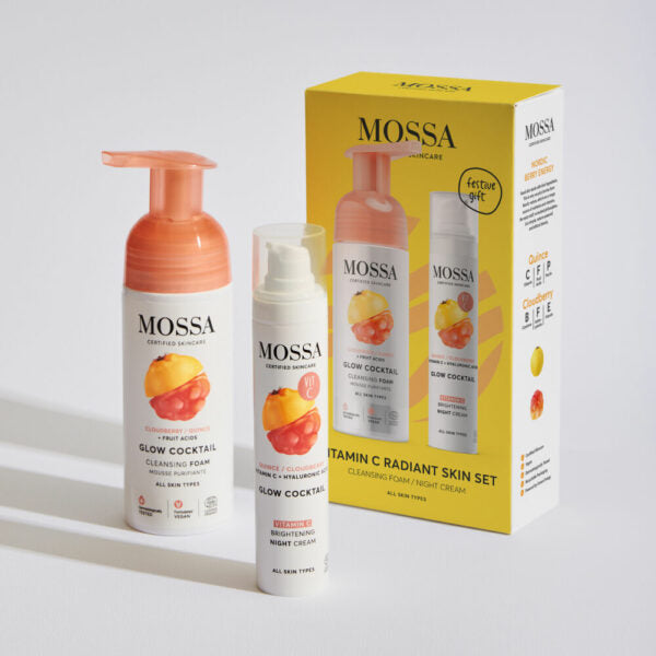 Mossa Vitamin C Lahjasetti; puhdistusvaahto ja yövoide, molemmat persikkaa ja C-vitamiinia sisältäen, aseteltuna eloisan keltaisen tuotelaatikon viereen houkuttelevin kuvin ja yksityiskohtaisin tiedoin; kaksi valkoista sylinterinmuotoista pakkausta mattapinnalla, toisessa pumppuannostelija, toisessa tuubinkorkki; molemmissa selkeät painetut etiketit, oranssit korostepalkit ja minimalistista groteskikirjasinta; laatikko pystyasennossa tarkoin hedelmäkuvin, teksti sisältää maininnan "Vitamin C".