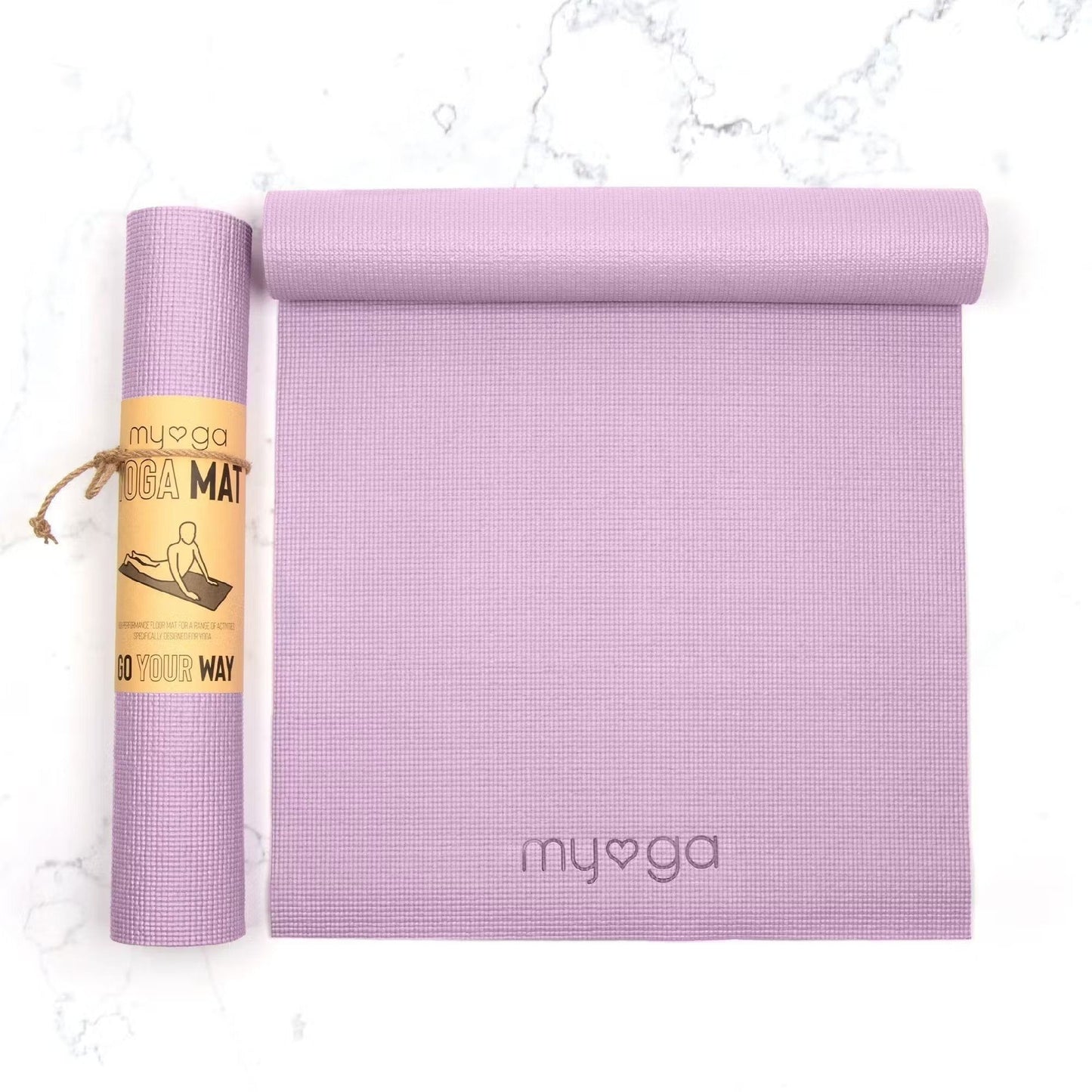 A rolled and unrolled lavender yoga mat with a myoga logo is displayed on a plain white surface. The mats are rectangular with a matte finish and slightly textured surface. The rolled mat is secured by a brown paper label, which shows an illustration of a person in a yoga pose and text in bold sans-serif font. No people or hands are present in the image.