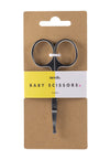 Needs Vauvan Kynsisakset; vauvansakset pyöristetyin kärjin, kiinnitetty ruskeaan mattapintaiseen pakkaukseen, merkitty ”needs.”; teksti ”BABY SCISSORS” ja ”14 grams” lihavalla groteskifontilla; sakset ovat valkoisin muovikahvoin ja metalliterin; pakkaus on suorakulmainen; keltainen ja valkoinen jaettu tausta, tasokuva; ei ihmisiä tai käsiä näkyvissä; sakset on suunniteltu turvallisiksi vauvan käyttöön.