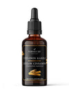 A dark amber glass dropper bottle of Nordicure Ceylon Cinnamon essential oil rests against a white background. The matte black label shows the brand name, “Ceylon Cinnamon” in English and Finnish, the botanical name, and has an illustration of cinnamon sticks. No people or hands are present in this simple studio shot.
