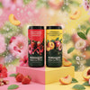 Nordqvist Sparkling Ice Tea Mansikka-Raparperi-Hibiskus: kaksi värikästä tölkkiä seisoo keltaisten ja pinkkien palikoiden päällä hedelmien ja kukanterälehtien ympäröimänä; mukana mansikoita, persikoita, teelehtiä ja kimalteleva kuplailmiö; tausta on eloisa ja epätarkka.