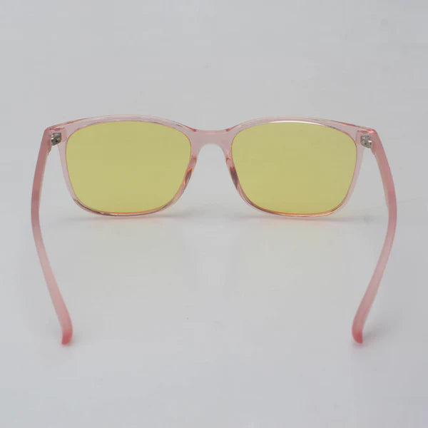 North Ray KAJO Sinivalo Päivälasit; silmälasit läpikuultavin vaaleanpunaisin muovikehyksin ja keltatummennetuin linssein, näytetty edestäpäin valkoista taustaa vasten; muoto pyöristetty ilman näkyvää brändäystä tai typografiaa; pinta kiiltäväpintainen; ei pakkausta, ihmisiä, käsiä tai tekstiä kuvassa.