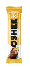 OSHEE Protein Bar Vanilla & Caramel; suorakulmainen OSHEE-proteiinipatukka kiiltävässä keltaisessa ja valkoisessa kääreessä, lihavoitu groteskiteksti ”NO sugar” ja ”27% protein”; kääreen kuvassa karamelli-vanilja-patukka avattuna näyttäen karamelli- ja suklaatäytekerrokset; tuote kuvattu vaaleaa taustaa vasten, ei ihmisiä tai käsiä.