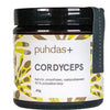 A brown, matte-finish jar with a screw-top lid displays the label “puhdas+ Cordyceps,” featuring yellow and green abstract designs and Finnish text. The container is cylindrical with clean edges. Label typography uses a simple sans-serif font. No people or hands are present. Background is plain white, image is a straightforward product shot.
