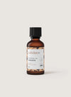 puhdas+ ESSENTIAL OIL CINNAMON -pullo, pieni meripihkanvärinen lasipullo mustalla muovikorkilla, pystyssä vaaleanbeigellä tasaisella taustalla; pullon pinta sileä ja kiiltävä; valkoisessa etiketissä mustaa ja ruskeaa tekstausvapaata tekstiä sekä geometrisia ruskeita kuvioelementtejä alaosassa; ei ihmisiä tai toimintaa kuvassa.