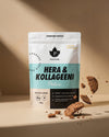 Puhdistamo Hera & Kollageeni Cookies & Cream; pystyssä seisova Puhdistamo Hera & Kollageeni -proteiinijauhepussi kollageenilisäyksellä, cookies & cream -maku, ympärillä murenevia keksinpaloja beigellä taustalla; pussi matta ja suorakulmainen, pääosin valkoinen, teksti selkeällä groteskilla; ei ihmisiä tai käsiä; kuva otettu suoraan edestä silmän korkeudelta.