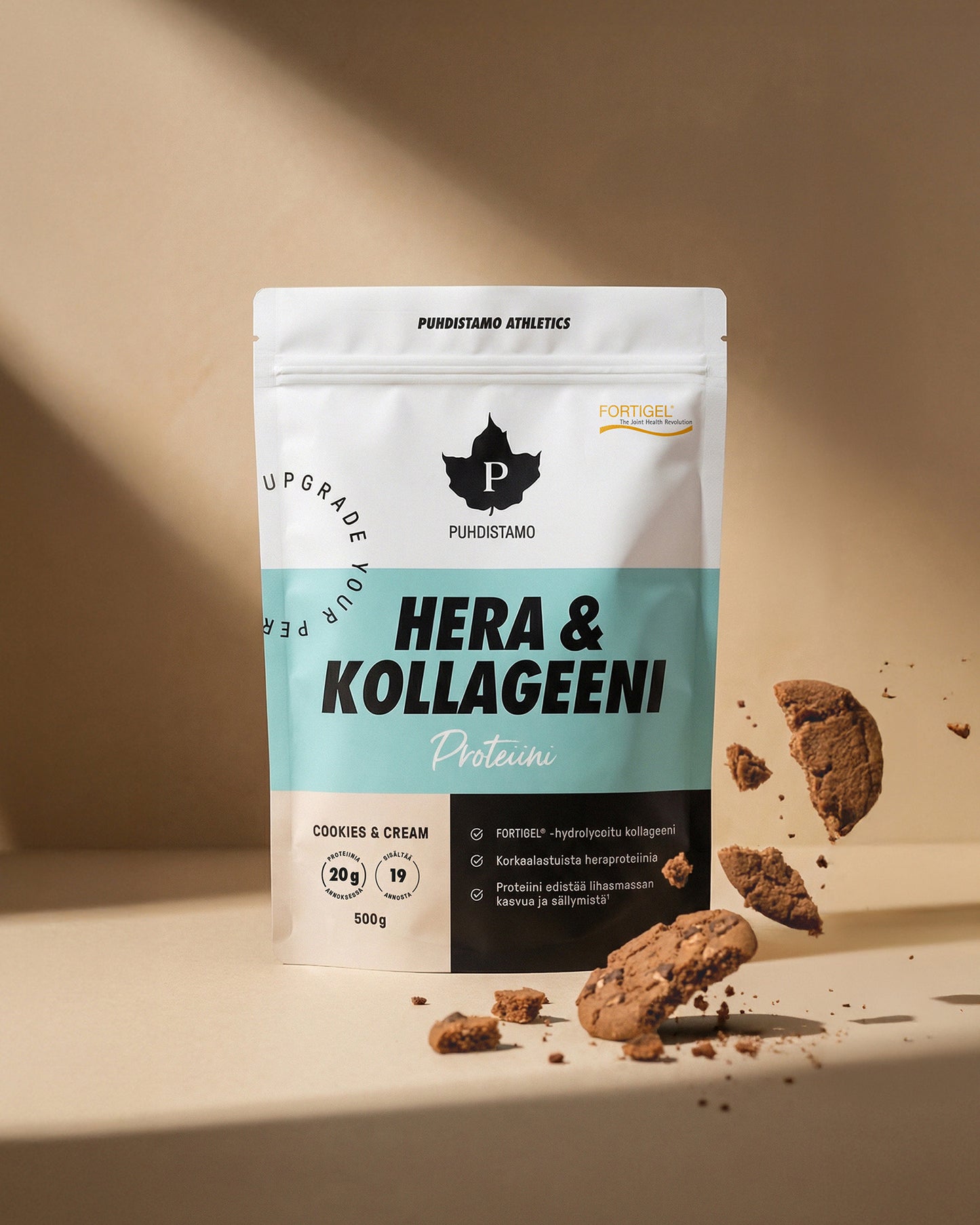 Puhdistamo Hera & Kollageeni Cookies & Cream; pystyssä seisova Puhdistamo Hera & Kollageeni -proteiinijauhepussi kollageenilisäyksellä, cookies & cream -maku, ympärillä murenevia keksinpaloja beigellä taustalla; pussi matta ja suorakulmainen, pääosin valkoinen, teksti selkeällä groteskilla; ei ihmisiä tai käsiä; kuva otettu suoraan edestä silmän korkeudelta.