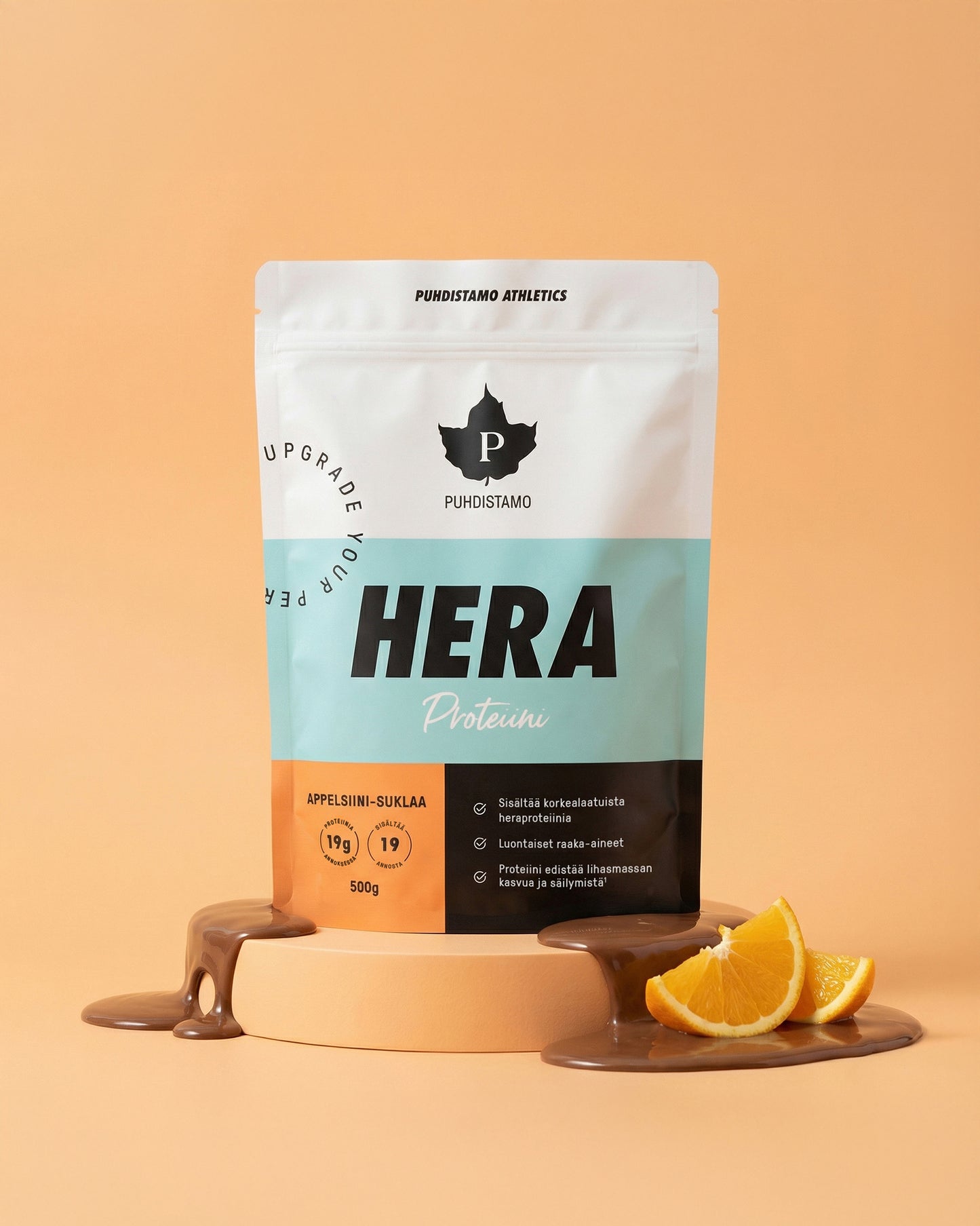 Puhdistamo Heraproteiini Appelsiini-Suklaa; Puhdistamo HERA-proteiinijauhepussi seisoo tasaisella pinnalla; pussi valkoinen mustalla ja ruskealla tekstillä, pinta matta, tuotenimi lihavoiduilla suuraakkosilla; ympärillä suklaakastikevanoja, pieni kasa heraproteiinijauhetta ja appelsiinilohkoja; tausta yhtenäisen persikanvärinen, ei ihmisiä tai käsiä kuvassa.