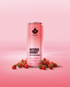 Puhdistamo Natural Energy Wild Strawberry: pinkki Puhdistamo Natural Energy Wild Strawberry -tölkki seisoo pystyssä pinkillä alustalla useiden kokonaisten metsämansikoiden ympäröimänä; tölkki on sylinterimäinen mattapinnalla ja näyttää valkoista ja punaista groteskitekstiä, mukaan lukien brändinimi ja ominaisuudet: kofeiini, elektrolyytit, ei lisättyä sokeria; tausta on yhtenäinen pinkki; ei ihmisiä tai käsiä näkyvissä.