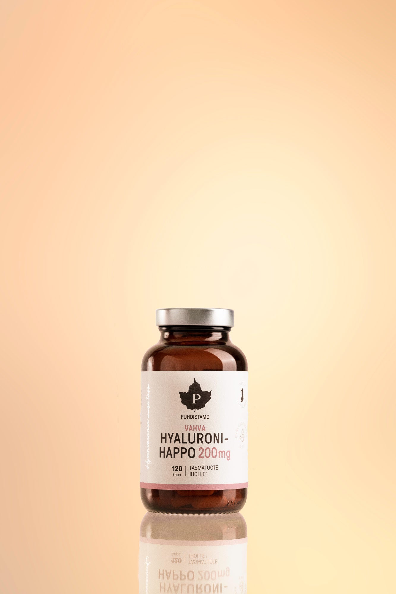 Puhdistamo Vahva Hyaluronihappo; ruskea lasipullo tekstillä Hyaluroni-Happo 200mg seisoo heijastavalla pinnalla persikanvärisen liukuvärin taustaa vasten; pullo lieriömäinen kiiltäväpinnalla, suljettu tummalla korkilla; etiketissä lihavoitua groteskitekstiä annostuksesta ja brändinimestä; pullo sisältää 120 kapselia hyaluronihappoa Puhdistamo-merkiltä.