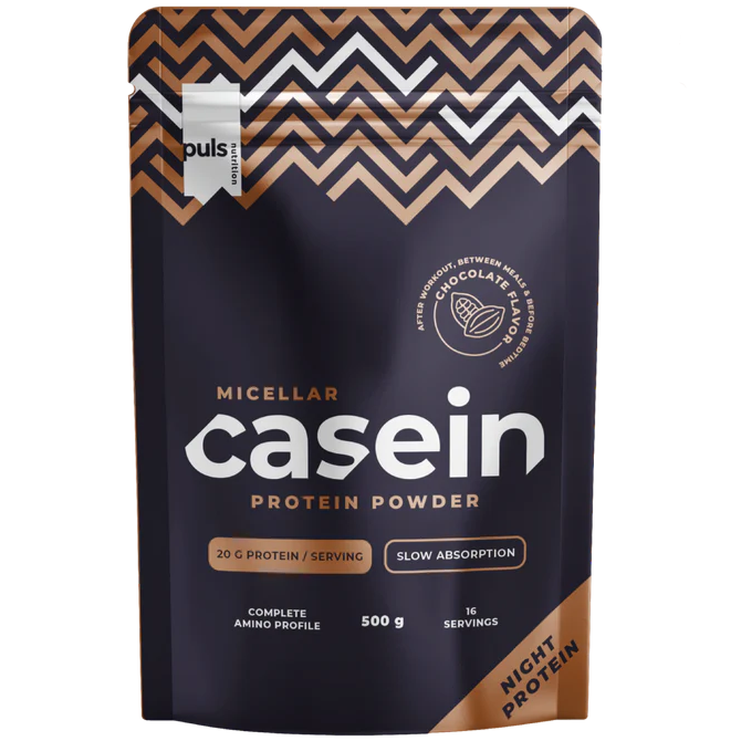 Puls Casein Protein Powder, maku Chocolate, 500 g; tumma pussi kulta- ja valkoisin tekstein, mattapintainen lohkokirjaimin metallikultaa ja valkoista; luettavissa hidas imeytyminen, 20 g proteiinia annosta kohti ja 16 annosta per pakkaus; ei ihmisiä tai käsiä; neutraali tausta, tuote täyttää kuva-alan.