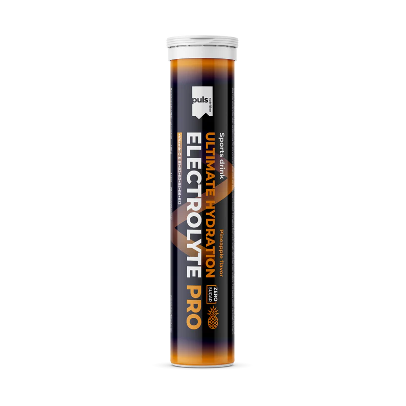 Puls Electrolyte Pro Poretabletti Ananas: korkea sylinterimäinen putkilo tekstillä "Ultimate Hydration Electrolyte Pro" merkiltä Puls, ananasmaku ja tarkoitettu urheilunesteytykseen; pakkaus näyttää siistin mustan, oranssin ja valkoisen yhdistelmän; groteskikirjasin pääetiketissä; pinta vaikuttaa kiiltävältä; ei ihmisiä tai käsiä näkyvissä, tausta on yksinkertainen ja vaalea, kuva on suoraan edestä otettu tuotekuva.