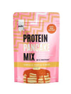 Puls Pancake Mix Vanilla-Maple Syrup, proteiinipannukakkujauheen pussi vanilja-vaahterasiirappimaussa; pakkaus vaaleanpunainen geometrisin kuvioin, etusivulla pino kuvitettuja pannukakkuja siirapin kera; pinta mattaa; lihavoitu valkoinen ja kultainen groteskiteksti kertoo tuotetiedot, mukaan lukien "Just add water!" ja "38g protein"; ei ihmisiä eikä käsiä näkyvissä, tausta neutraali, kuva suoraan edestä.