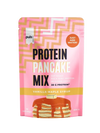 Puls Pancake Mix Vanilla-Maple Syrup, proteiinipannukakkujauheen pussi vanilja-vaahterasiirappimaussa; pakkaus vaaleanpunainen geometrisin kuvioin, etusivulla pino kuvitettuja pannukakkuja siirapin kera; pinta mattaa; lihavoitu valkoinen ja kultainen groteskiteksti kertoo tuotetiedot, mukaan lukien "Just add water!" ja "38g protein"; ei ihmisiä eikä käsiä näkyvissä, tausta neutraali, kuva suoraan edestä.