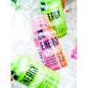 Puls Energy Shot Tropical; värikkäitä kiiltäväpintaisia energiajuomapulloja esillä, etualalla pinkki pullo selkeällä lihavoidulla tekstillä "Energy Shots"; taustalla vihreitä ja violetteja pulloja; kaikki pullot sylinterinmuotoisia kapein kauloin ja ruuvikorkein; tuotteiden ympärillä jääpaloja tasaisella alustalla; ei ihmisiä tai käsiä kuvassa.