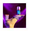 A foot in a gold sock and lavender high-heeled sandal is raised, elegantly balancing a bottle of nourishing hair oil on the sole. The transparent cylindrical bottle has a white label with black text and a gold cap. No hands or other people are present. The background is purple with dramatic lighting.