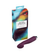 A purple vibrator with a smooth matte surface and rounded shape is positioned beside a rectangular box. The box has bold block colors—blue, yellow, orange—in an abstract pattern and features the legible label “On Spot Stimulator Multi Speed Vibrator by Risu” in clear, sans-serif font. The products rest on a plain white background in a simple product shot.