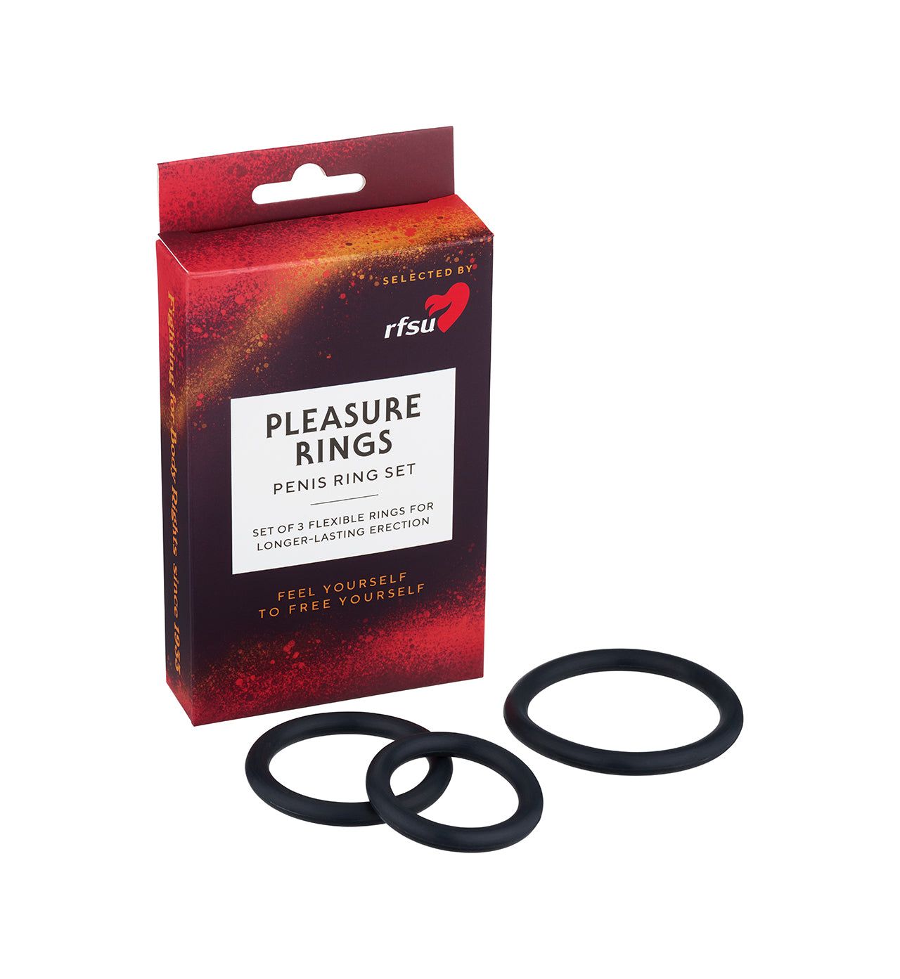 A red rectangular box labeled “Pleasure Rings Penis Ring Set” stands upright on a white, matte surface. Three black silicone rings with smooth, matte finishes and different diameters are placed side by side next to the box. The product label uses bold, white sans-serif text. No people or hands are present in the shot.