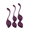 Three purple silicone kegel exercise balls of varying sizes, each with a long, curved retrieval handle, displayed upright against a white background. The silicone has a matte finish. There is no visible packaging or label text. No people or hands are present in the image. The shot is straightforward and product-focused.