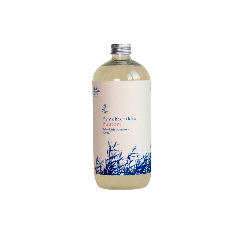 A clear plastic bottle containing light yellow liquid, cylindrical in shape with a white screw cap. The matte white label has blue grass illustrations and Finnish text printed in clean, sans-serif font. Only the words “Pyykkietikka Puuteri” are legible on the label. The product is photographed against a plain, light background with no people or hands visible.