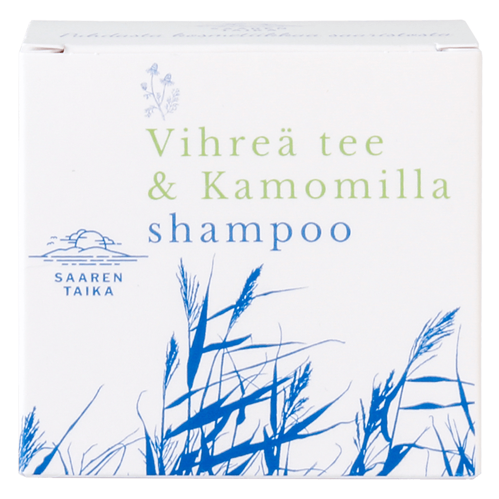 Saaren Taika Palashampoo Vihreä Tee & Kamomilla, valkoinen pakkaus sinisellä ja vihreällä tekstillä "Vihreä tee & Kamomilla"; pakkauksessa sinisiä ruohokuvituksia ja Saaren Taika -logo; pakkaus suorakaiteen muotoinen ja mattapintainen, tuotenimi lihavoidulla monivärisellä groteskifontilla; kuvattu suoraan edestä vaaleaa taustaa vasten, ei ihmisiä eikä käsiä näkyvissä.