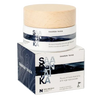 A jar of Saaren Taika Ruusunmarja Kamelia anti-age face cream sits atop its matching box, featuring minimalist white, blue, and wood-toned packaging with bold text and nourishing rosehip. The jar is cylindrical with a matte white finish and a light wood-colored flat lid. The label has bold black sans-serif text. The box repeats the same colors and fonts as the jar. Background is a seamless white surface. No people or hands are present in the image. This is a centered studio product shot at eye level.