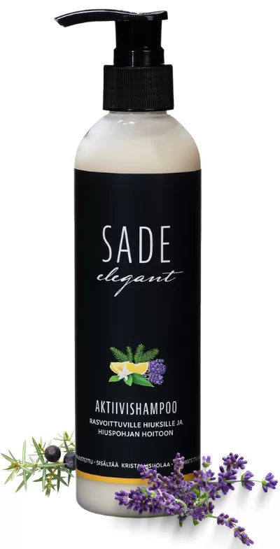 Sade Aktiivishampoo; pullo SADE elegant -shampoolle mustalla etiketillä, yrttejä ja laventelinkukkia sen vieressä; pullo lieriön muotoinen muovia mattapinnalla; etiketissä valkoinen sans-serif-teksti kertoo tuotenimen ja käyttötarkoituksen suomeksi; ei ihmisiä tai käsiä; neutraali tausta ja lähikuva.