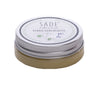 A small round tin of SADE classic pihka-suolasalva, a Finnish natural resin salve, with a matte silver screw-top lid. The white label wraps around the top and side, showing green sans-serif text and stylized floral line graphics. Product name and Finnish description are clearly legible. The container is photographed alone against an untextured surface.