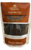 Saharogya Luxury Tea -pakkaus, merkitty Peach Detox, monivärisellä koristekuviolla suorakaiteen muotoisessa mattapintaisessa pussissa; etusivulla läpinäkyvä ikkuna näyttää irtoteelehdet; typografia lihavoitua ja selkeää; ei ihmisiä tai käsiä näkyvissä; tausta yksinkertainen suoralla tuotevalaistuksella.