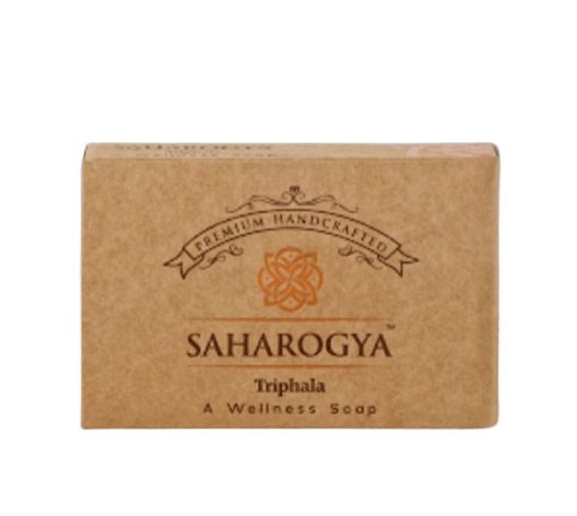 A brown, rectangular cardboard box with a matte finish, labeled Saharogya Triphala Wellness Soap. “Premium Handcrafted” is printed above the product name in a simple sans-serif font. The packaging shows clear corners and edges, with all text aligned horizontally. The box is displayed on an untextured light background in a standard product shot.