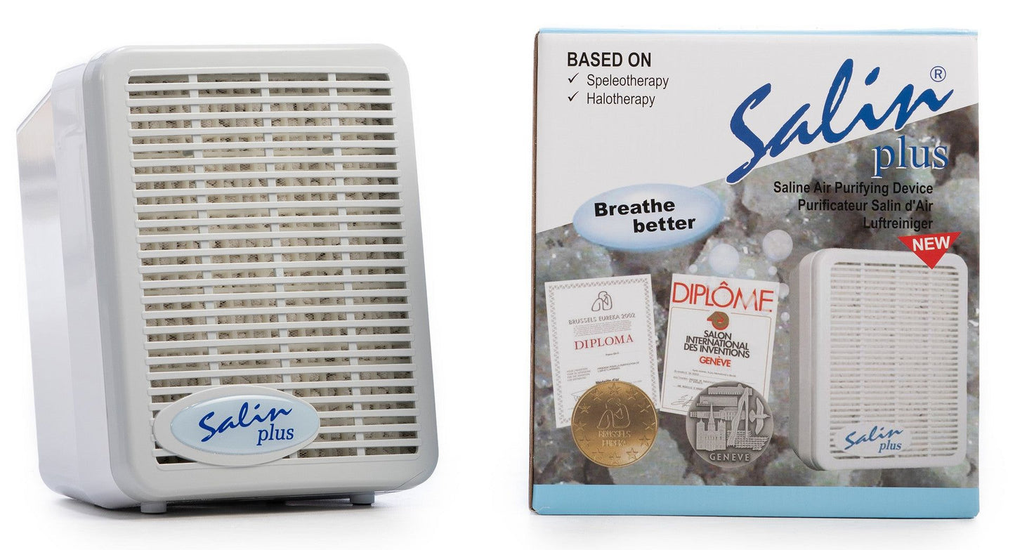 A Salin Plus air purifying device is shown next to its packaging box, which displays product details and awards. The device is white with a rectangular form, vented front panel, and matte surface. The cardboard box features printed product information and award icons in clear sans-serif fonts. Both items are placed upright against a plain white background in a studio shot.
