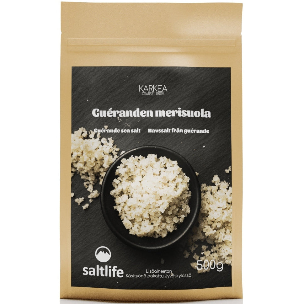 Saltlife Guérande Merisuola Karkea; 500 g ruskea Saltlife Guérande -merisuolapakkaus, suorakaiteen muotoinen ja valmistettu mattapintaisesta paperimateriaalista; etuosassa karkeaa valkoista suolaa pyöreässä kulhossa ja hajallaan tekstuurisella tummalla pinnalla; monikielinen teksti painettu pystysuunnassa selkeällä groteskifontilla; ei ihmisiä tai käsiä; lähikuva vaalealla taustalla.
