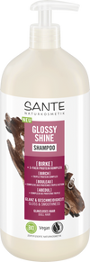 Sante Glossy Shine Shampoo; pullo koivunuutteella rikastettua shampoota, merkitty vegaaniseksi ja luomuksi kiiltäville ja sileille hiuksille; muovipullo on valkoinen mattapinnalla, ruskeita ja vihreitä etikettielementtejä, pumppuannostelija; etikettiteksti on groteskia; ei ihmisiä tai käsiä näkyvissä; tausta yksivärinen, kuva suoraan edestä.