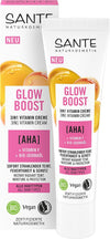 Sante Glow Boost 3 in 1 Vitamiinivoide; tuubi ja laatikko AHA-hapolla, F-vitamiinilla ja luomu-jojobaöljyllä rikastettua 3-in-1-vitamiinivoidetta; molemmat pakkaukset ovat suorakulmaisia; tuubi on mattapintainen, pääosin valkoinen keltaisin korostein; etiketit ilmoittavat sopivuuden kaikille ihotyypeille, vegaanisuuden, sertifioidun luomulaadun ja luomu-ainesosat; groteskikirjasinta pakkauksissa; tausta neutraali, ei ihmisiä tai käsiä näkyvissä.