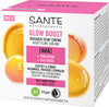 Sante Glow Boost Sävyttävä Kasvovoide; laatikko, jonka teksti kertoo ainesosista – AHA, hyaluroni ja luomu-ruusu – korostaen vegaani- ja luomusertifiointia; sopii kaikille ihotyypeille, pakkaus koristeltu iloisin keltaoranssein kuplakuvituksin; suorakulmainen laatikko mattapinnalla, pääosin valkoinen keltaoranssein korostein, groteskitypografia mustana ja oranssina; ei ihmisiä tai käsiä näkyvissä; tausta yksivärinen ja hyvin valaistu; kuva näyttää vain pakkauksen etupuolen.