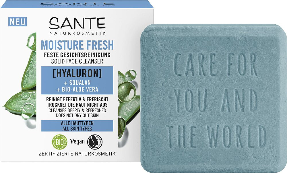 Sante Moisture Fresh Kasvosaippua; sininen Sante Moisture Fresh -kiinteä kasvopuhdistuspala vaaleansinisenä suorakulmaisena, mattapintainen ja kohokuvioitu teksti "Care for you and the world", laatikkopakkauksensa vieressä; laatikko esittää vihreitä aaloe vera -viipalekuvia ja tuotetietoja: vegaaninen, luomu, kosteuttava; tausta valkoinen, ei ihmisiä näkyvissä.