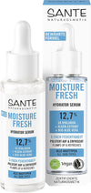Sante Moisture Fresh Kasvoseerumi; pullo ja laatikko kosteuttavaa seerumia hyaluronilla, levän uutteella ja aaloe veralla; rikastettu vegaanisin ainesosin, sopii kaikille ihotyypeille, merkitty sertifioiduksi luonnonkosmetiikaksi; pullo on puolikirkas valkoinen pumppukorkilla, laatikko suorakulmainen vihreä-valkoisin mattapinnoin; molemmissa modernia groteskitekstiä; ei ihmisiä tai käsiä näkyvissä; tausta valkoinen, kuva suoraan edestä tasaisessa valaistuksessa.