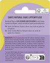 Sante Natural Care Huulivoide; Sante Natural Care -huulivoidepakkauksen takaosa, esittää tuotekuvaukset saksaksi, ranskaksi ja espanjaksi, ainesosaluettelon, sertifiointilogot, viivakoodin, kierrätysmerkit ja violetti-keltaiset korostukset; suorakulmainen läpipainopakkaus mattapinnalla selkein painetuin osioin; groteskikirjasin käytössä kauttaaltaan; ei ihmisiä tai käsiä; valkoinen tausta, lähikuva.