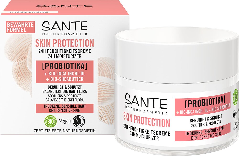 Round jar with matte pink lid and white base, paired with a rectangular box in matching pink and white colors. Packaging displays sans-serif type in black and pink. Both jar and box feature the product name and main ingredients. Background is plain white, no people or hands are shown. SANTE Skin Protection 24H Moisturizer with probiotics, bio-Inca inchi oil, and bio-sheabutter nourishes dry, sensitive skin. This vegan, certified natural cosmetic comes in a pink and white jar with a matching box.