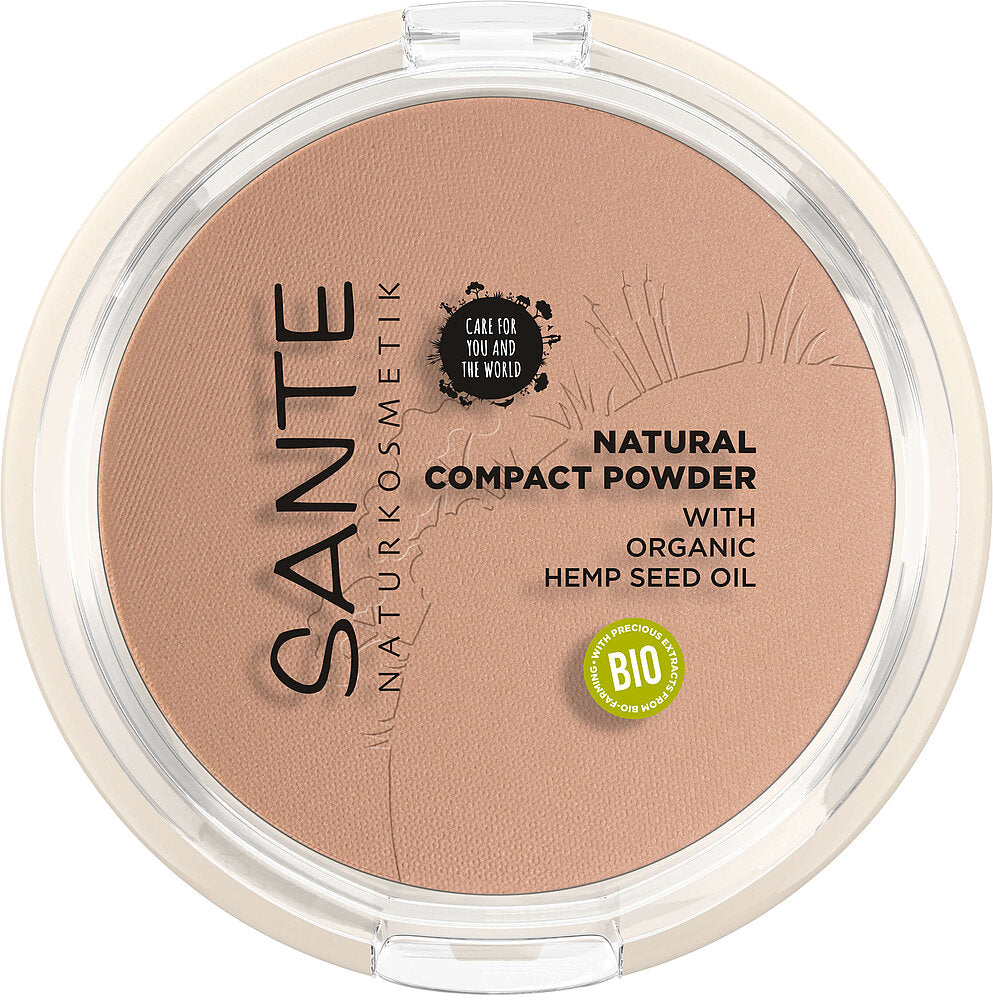 Sante Kivipuuteri; pyöreä Sante Natural Compact Powder -rasia luomu-hamppusiemenöljyllä beigen sävyssä; pyöreä läpinäkyväkantinen muovirasia sisällä mattapuuteria; kannessa painettu tuotenimi groteskikirjasimella ja vihreä Bio-sertifiointimerkki; ei ihmisiä tai käsiä; tausta tasainen, kuva otettu suoraan ylhäältä.