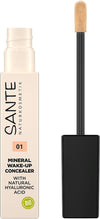 Sante Nestemäinen Peitevoide; tuubi Sante Mineral Wake-Up Concealer -peitevoidetta mustalla sivellinapplikaattorilla; tuubi sylinterin muotoinen muovia mattapinnalla; etiketin kirjasin selkeä groteski valkoisella ja mustalla; luettavissa sävy 01 ja maininta luonnollisesta hyaluronihaposta, mineraalipigmenteistä ja bio-ainesosista; tuote valkoista taustaa vasten studiokuvassa; ei ihmisiä tai käsiä.