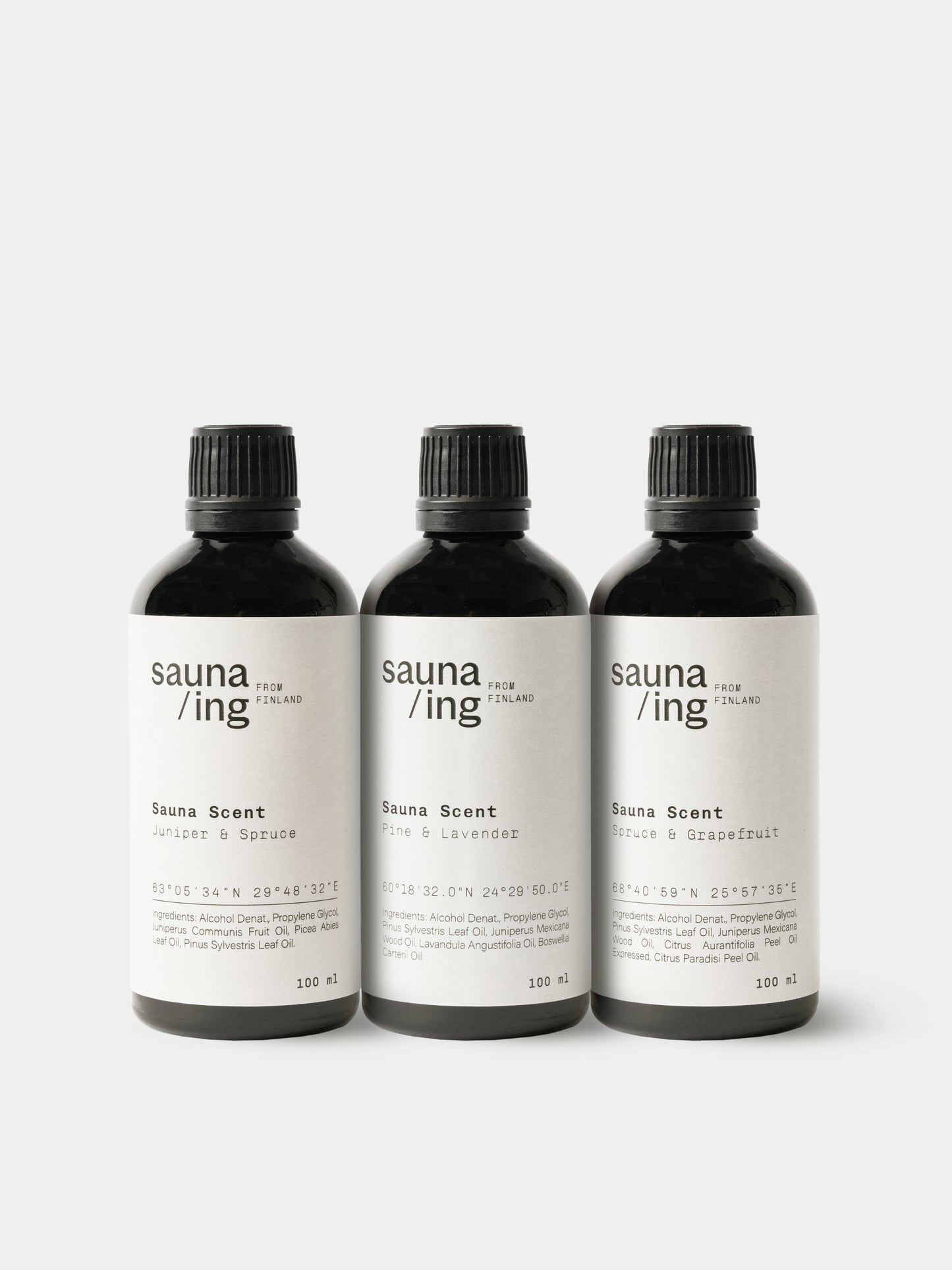 sauna/ing Sauna Scent Spruce & Grape; kolme mustaa mattapintaista pulloa seisoo rinnakkain; jokaisessa selkeä moderni typografia sauna /ing ja tuoksujen nimet: Juniper & Spruce, Pine & Lavender ja Eucalyptus & Grapefruit; pullot lieriömäisiä yhtenevin mustin kansin; tausta valkoinen.