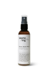 sauna/ing Sauna Serum Mist; ruskea lieriömäinen pullo mattapinnalla, musta muovinen suihkesuutin ja valkoinen suorakaiteen muotoinen etiketti; teksti yksinkertaisella groteskifontilla Sauna Serum Mist sekä maininta OCEANBOOST™ #4 Collagen Booster; pullon koko 100 ml; neutraali tausta, ei ihmisiä tai käsiä; tuote sisältää kollageenia tehostavia ravitsevia ainesosia.