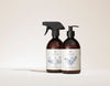SEES x Moomin Dish Wash Spray; kaksi ruskeaa pulloa valkoisin etikettein ja mustin pumpuin, toisessa suihkesuutin ja toisessa työntöannostelija, merkitty SEES ja koristeltu minimalistisin viivapiirroksin, kasvikuvituksin ja luonnollisen tyylikkyyden tuntua vaaleaa taustaa vasten; molemmissa pulloissa lieriömäinen lasirunko mattapinnalla; etiketit valkoisia yksinkertaisin mustin groteskitekstein; asetelma tasaisesti valaistu, näyttää vain tuotteet ilman ihmisiä tai käsiä.