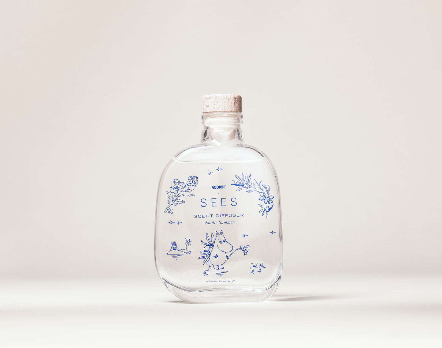 SEES x Moomin Room Diffuser Nordic Summer; kirkas lasipullo korkkikannella, tekstillä SEES SCENT DIFFUSER Nordic Summer, sinisiä kasvikuvituksia ja pieni piirroshahmo etuosassa; etiketin typografia sinistä groteskia; pinta kiiltäväpintainen; pullo lieriömäinen ja läpinäkyvä; ei ulkopakkausta näkyvissä; vaalea murrettu valkoinen tausta ilman lisärekvisiittaa tai ihmisiä; suoraviivainen tuotekuva silmän korkeudelta.