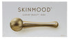 Kultainen kasvorulla, jossa merkintä SKINMOOD ja teksti Luxury Beauty - Roller, esiteltynä tyylikkäästi valkoisella pakkauksella, sopii kohottamaan ihonhoitorutiinia; kultainen lieriömäinen rullatyökalu metallisella viimeistelyllä; kahvassa selkeä musta groteskiteksti SKINMOOD ja Luxury Beauty - Roller; rullassa pyöristetyt päät; valkoinen suorakaiteen muotoinen rasiatausta, ei ihmisiä tai käsiä; studiovalaistus tasaisella pinnalla.