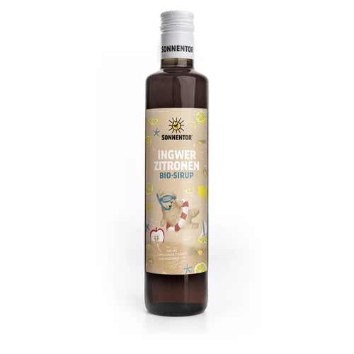 Pullo Sonnentor Ingwer Zitronen Bio-Sirup -siirappia valkoisella kierrekorkilla; pullo on lasia ja lieriömäinen sileäpintainen. Etiketissä on mattapinta, värillisiä kuvituksia auringosta, inkiväärinjuuresta, sitruunaviipaleista ja karhu makaa ilmapatjalla juoma kädessä. Tuoteteksti on selkeällä pääteviivattomalla fontilla. Neutraali studiotausta; ihmisiä tai käsiä ei näy.